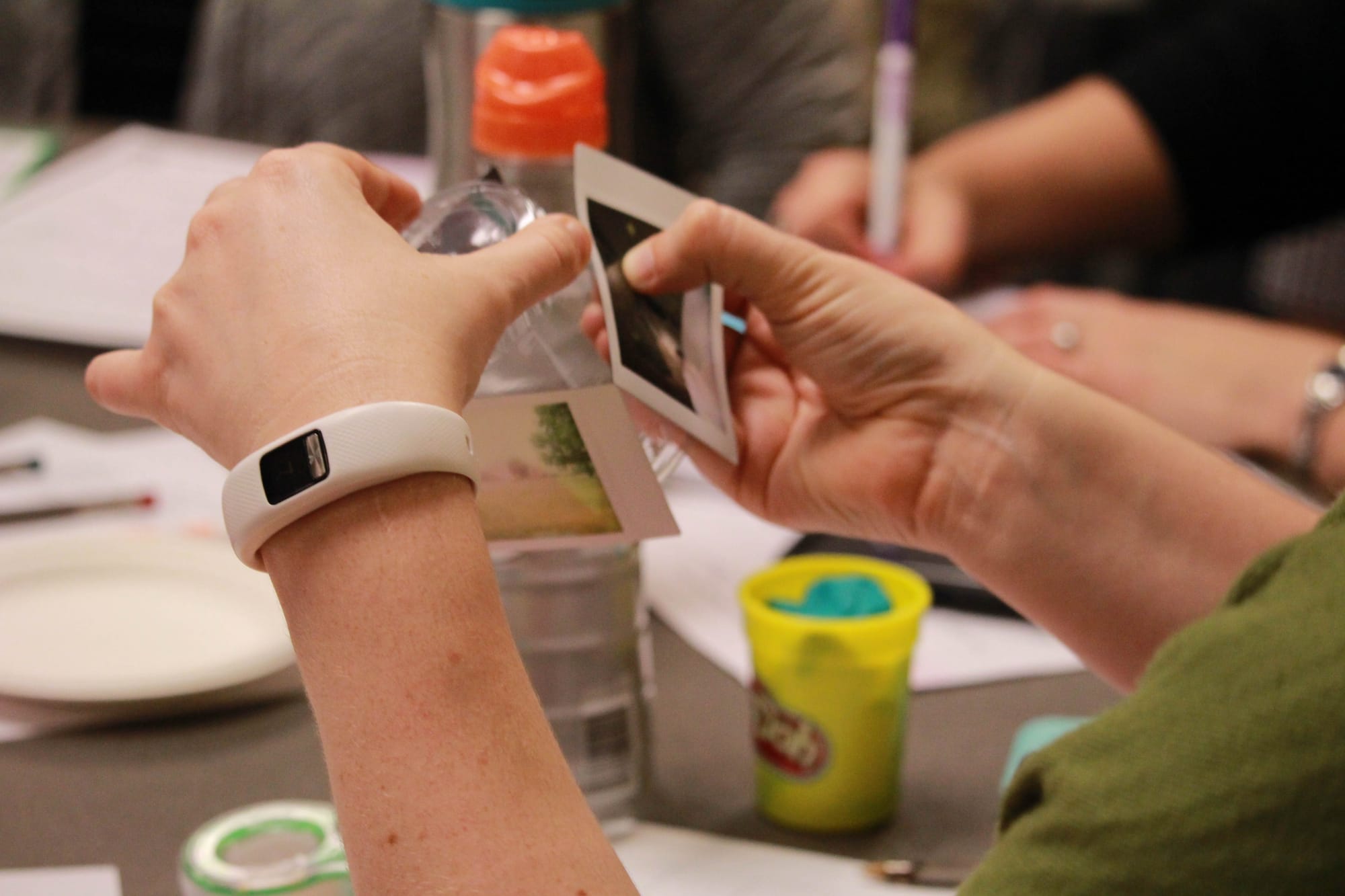 person's hands attaching Polaroid photographs to the surface of a bottle