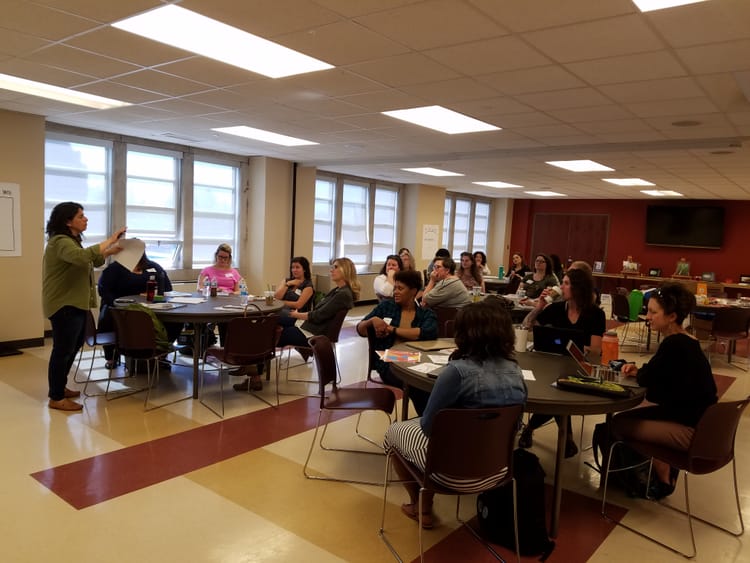 group of people sitting at round tables within a classroom