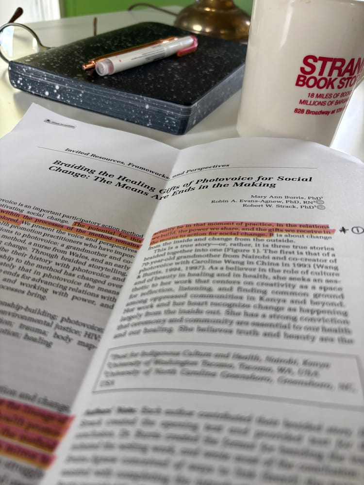 first page of a journal article with highlighted portions and marginalia atop a writing desk