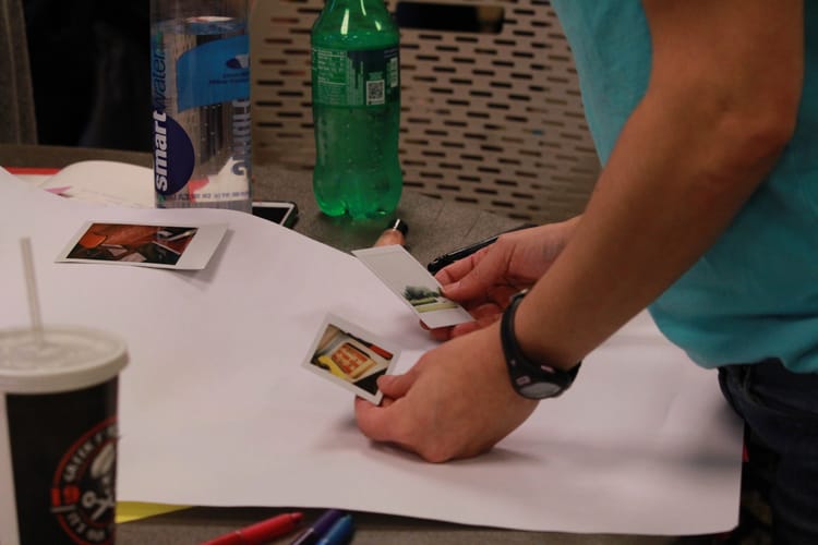 woman's arms holding two instant photographs over a table